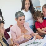 A family discusses property plans with a realtor indoors, focused on purchasing a new home.